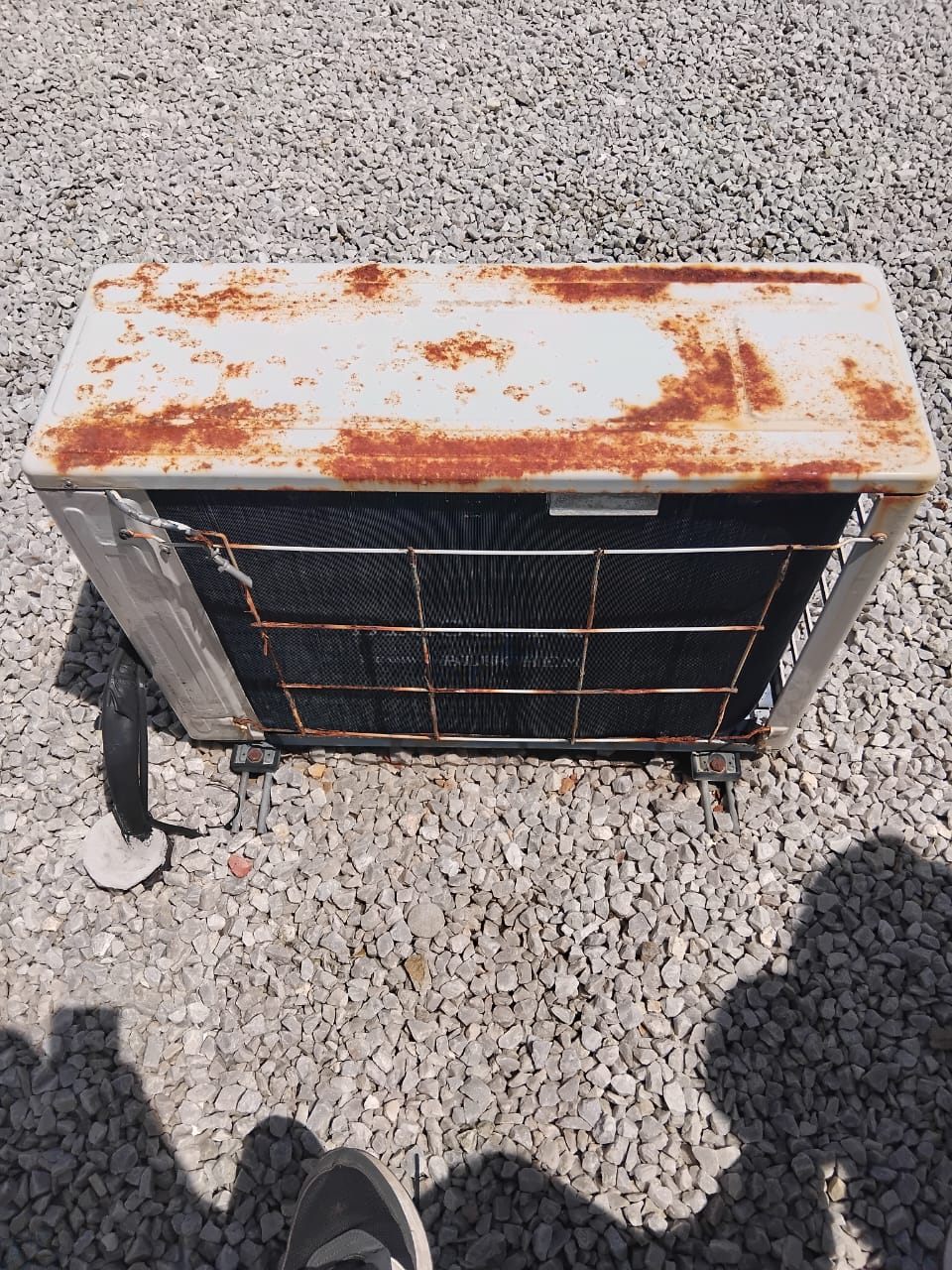 Heavily rusted top panel and fan guard on an aircon outdoor unit