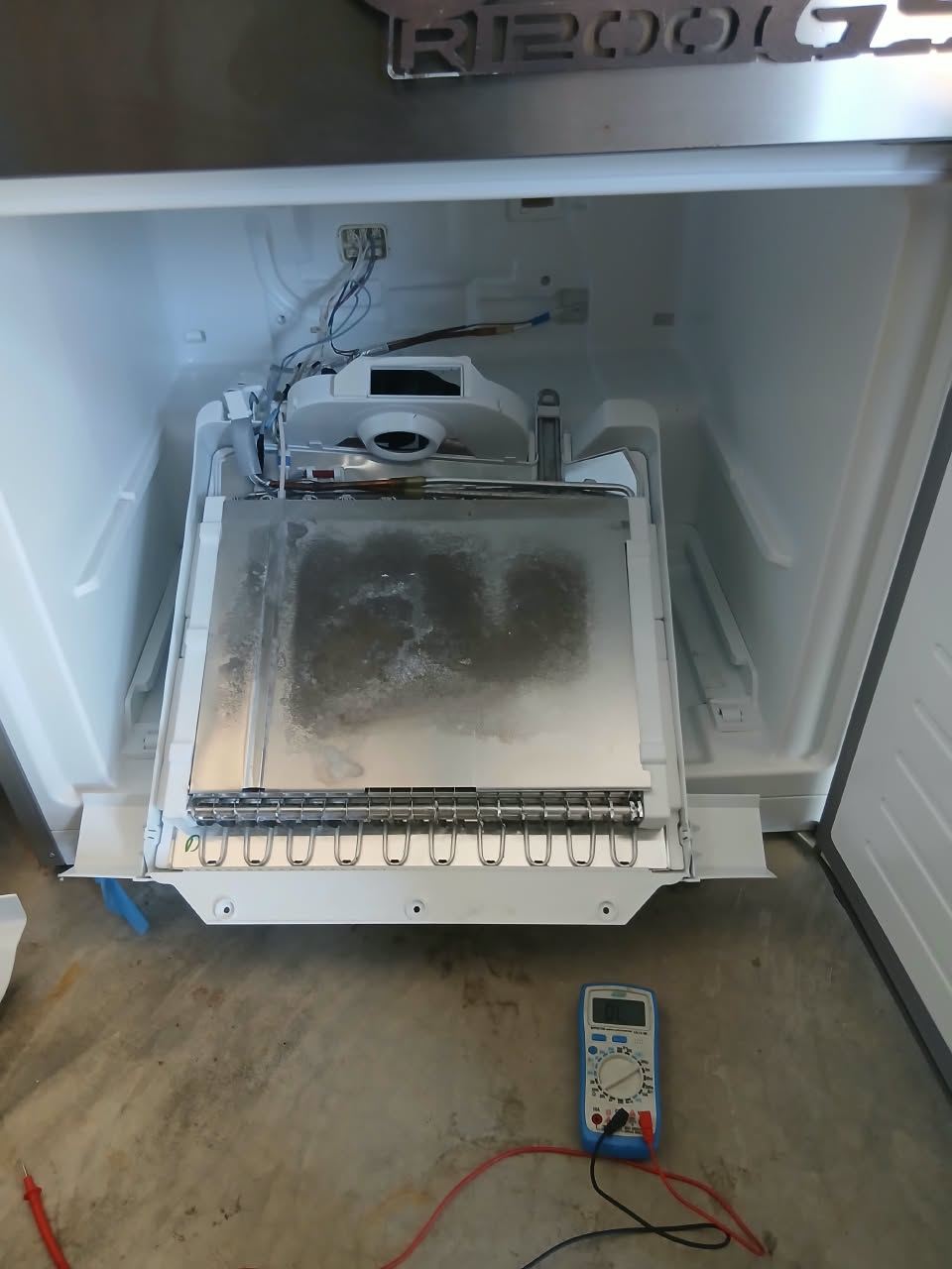 Bosch fridge freezer section opened up while a technician tests components with a multimeter in Midstream