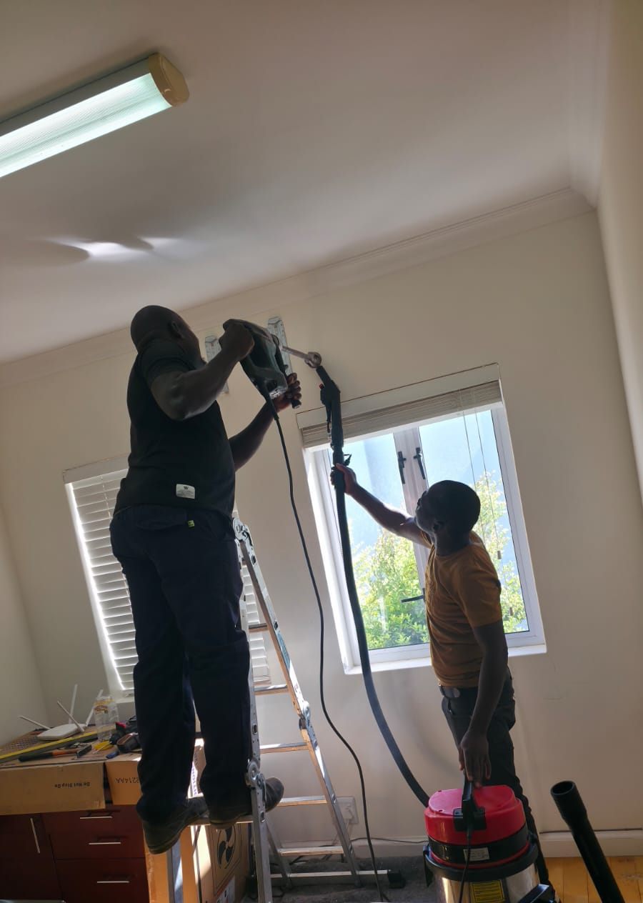 Technicians drilling an aircon pipe hole with a vacuum catching the dust