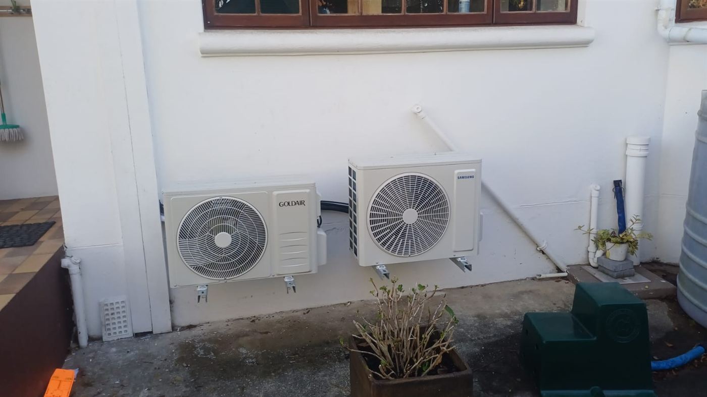 Two aircon outdoor units mounted on brackets along a wall in Hyde Park