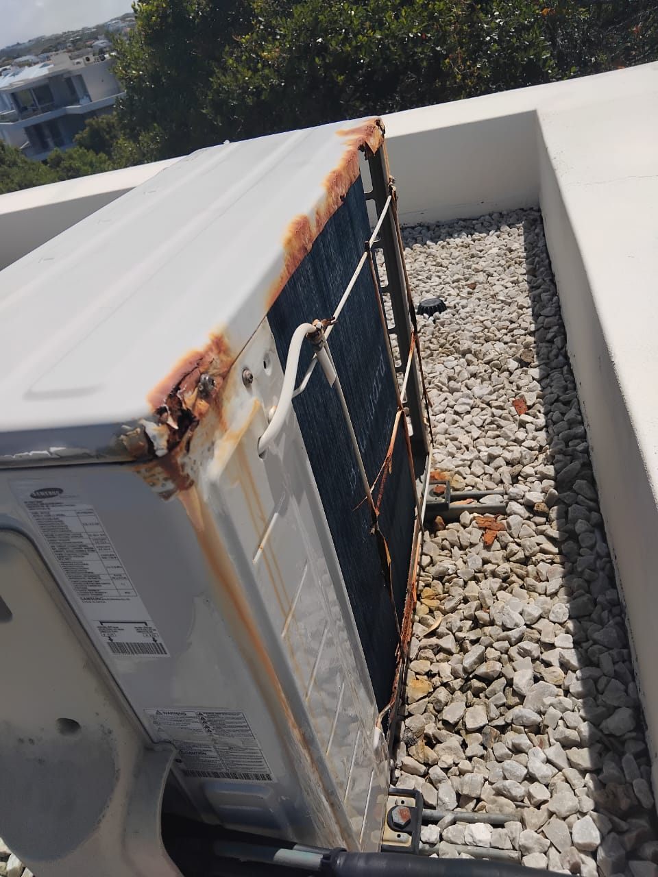 Rusted casing and corroded edges on an aircon outdoor unit on a rooftop in Kempton Park